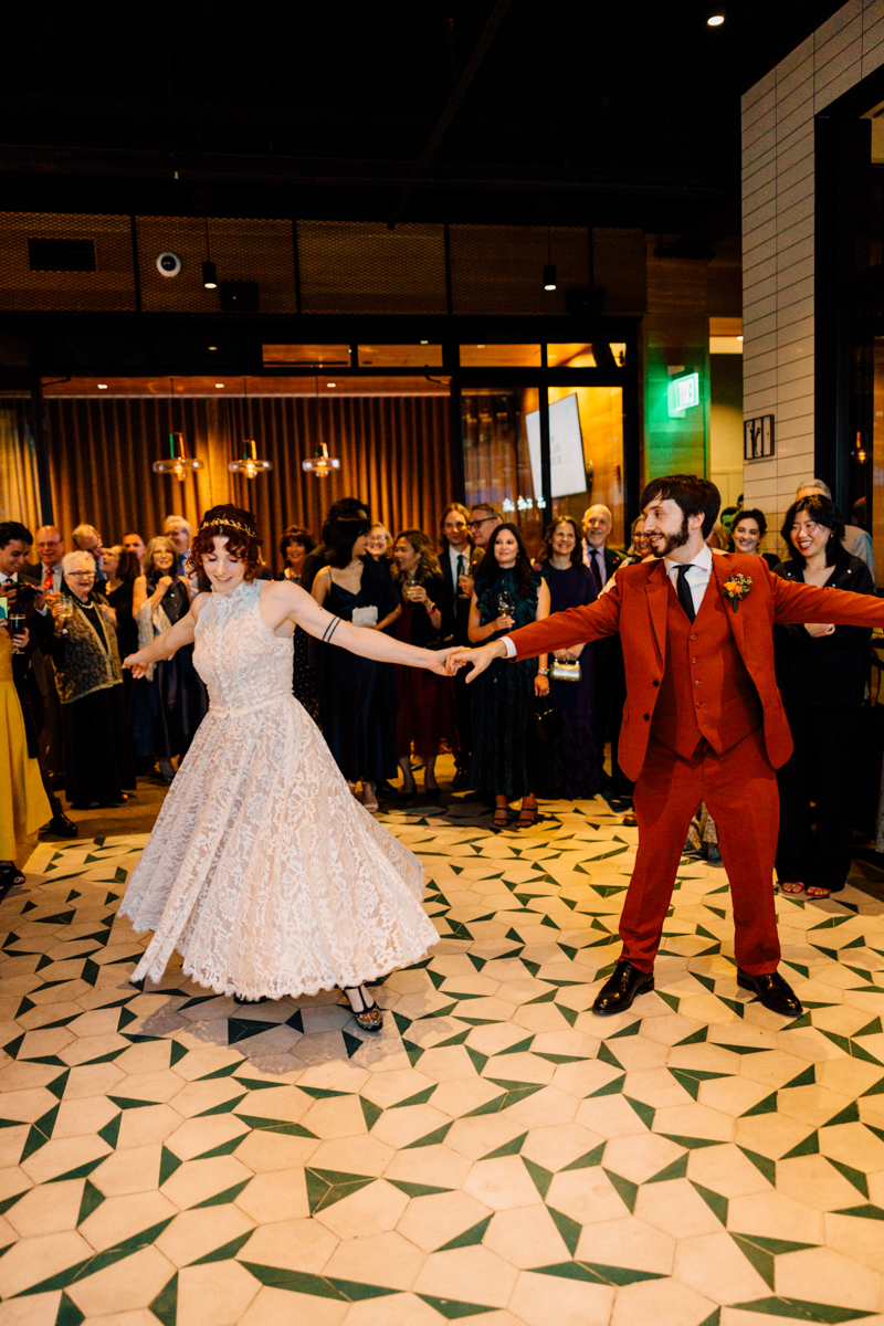 A couple showcasing their first dance in a vibrant venue, surrounded by an enthusiastic audience.