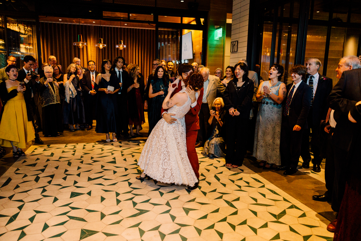 A couple shares a dance while guests enjoy the moment, surrounded by elegant decor and lively expressions in a festive atmosphere.