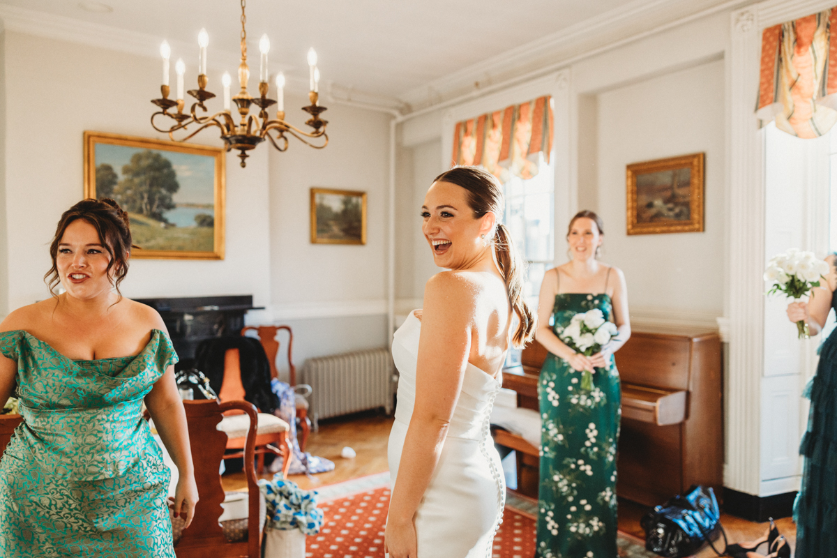 A bride and her bridesmaids share smiles and laughter in a beautifully decorated room, preparing for the wedding.