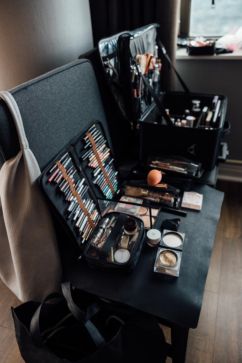 A collection of makeup products and tools organized on a table, featuring cosmetic bags, brushes, and various beauty items.