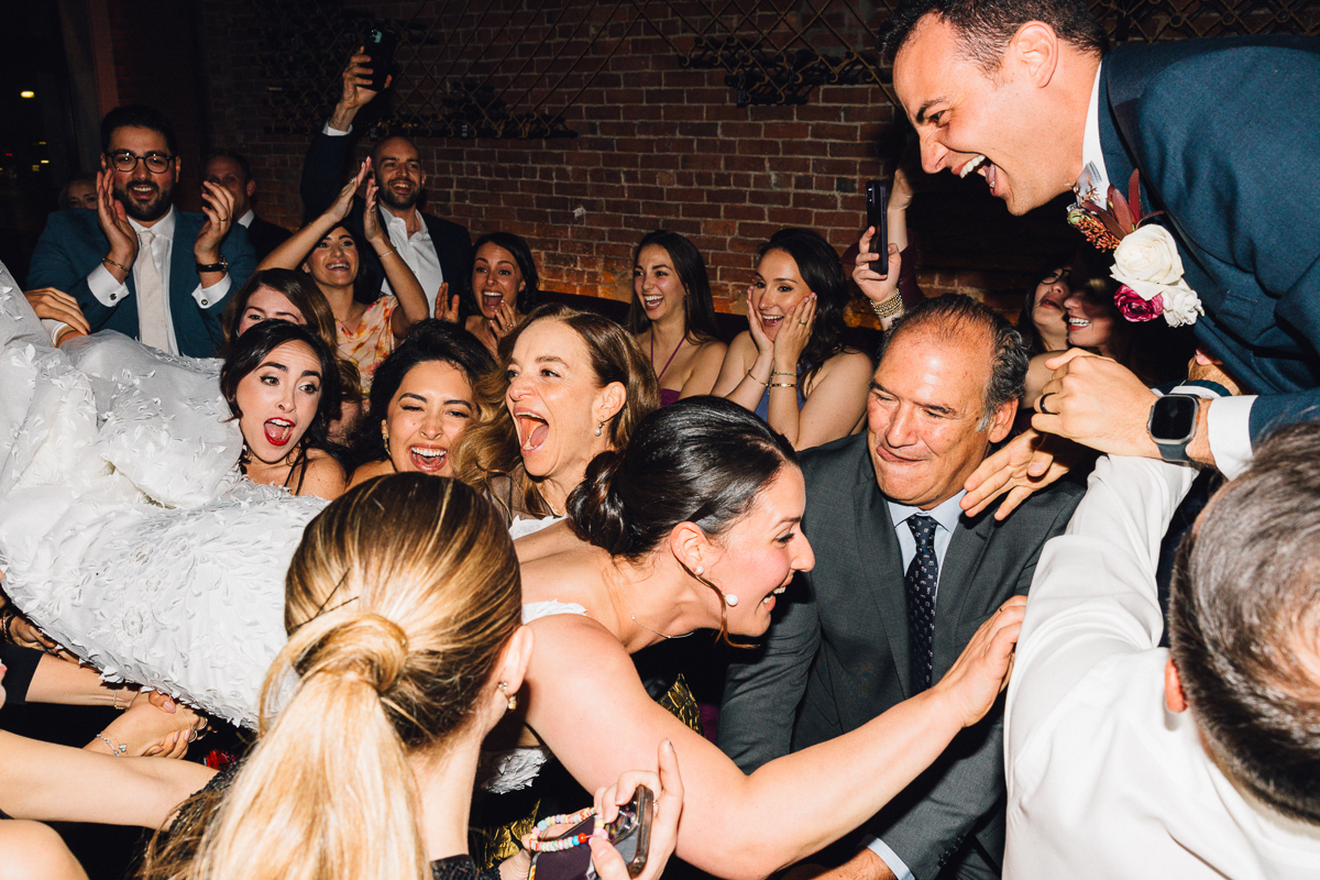 A lively group of wedding guests cheering and celebrating, capturing the joyous moments of a wedding reception.