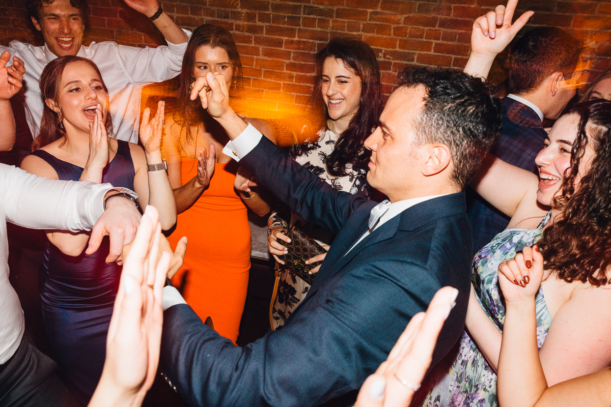A group of friends joyously dancing and celebrating together in a lively atmosphere, with hands raised and smiles all around.