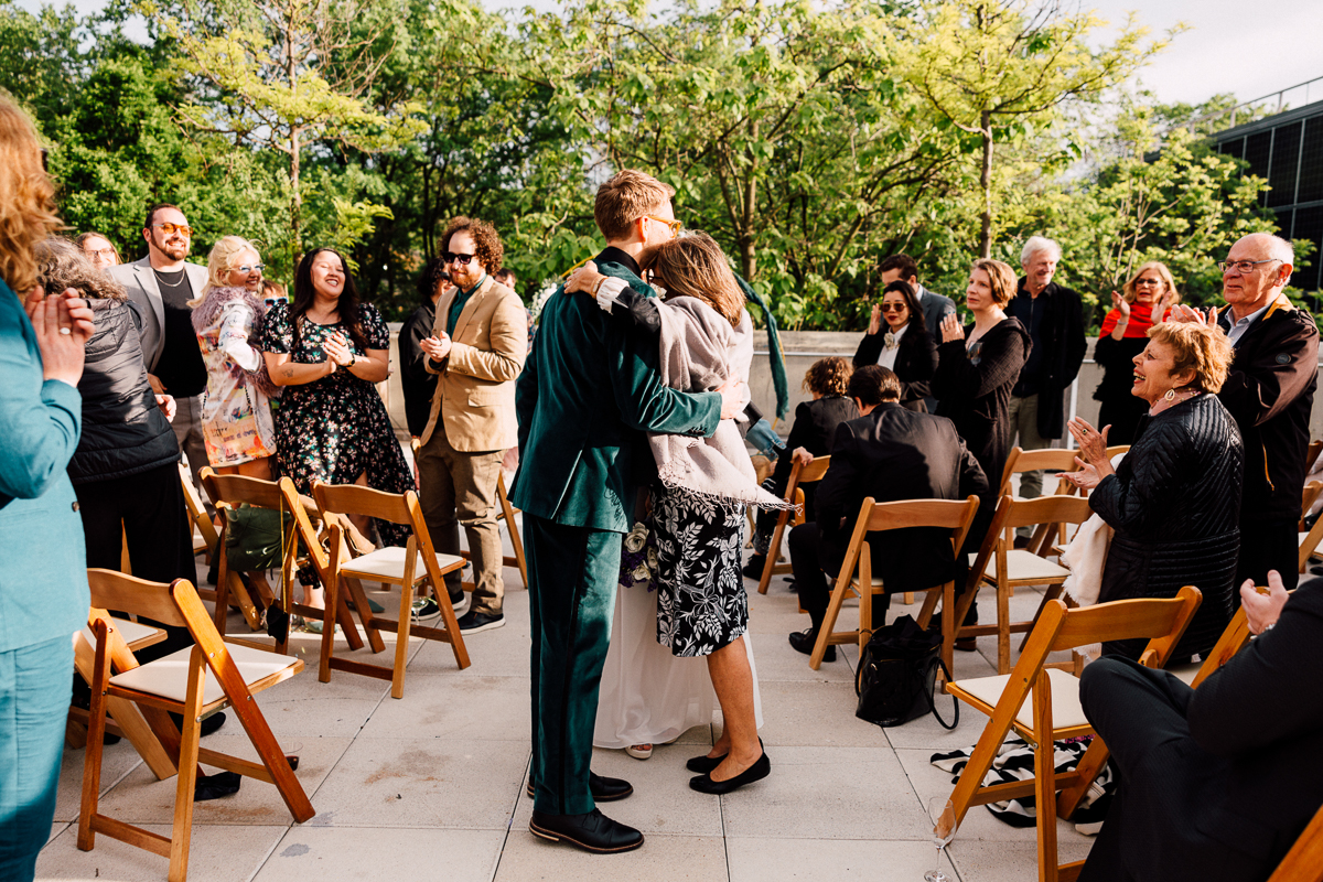 Guests joyfully celebrating as a couple shares a heartfelt hug during an outdoor event.