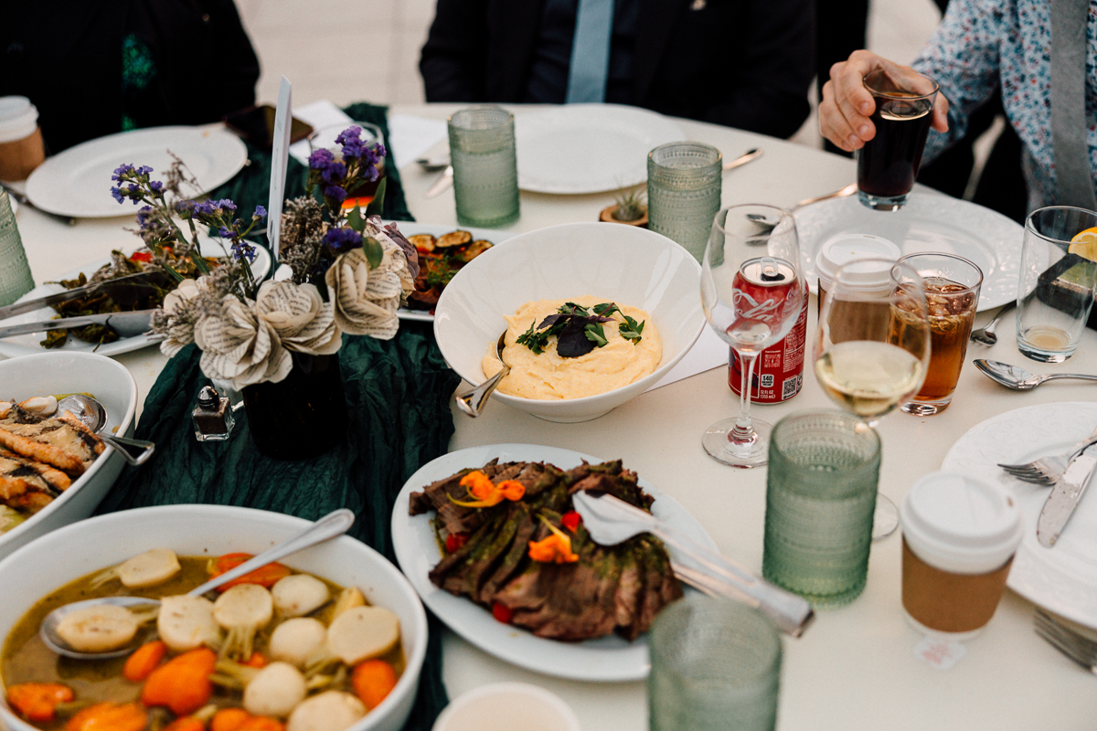 A beautifully arranged dinner table featuring various dishes, drinks, and floral decorations.