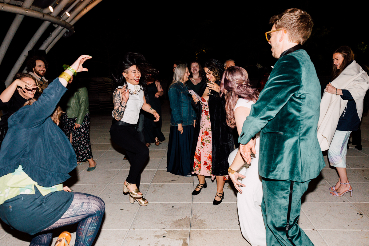 A lively group of people dancing joyfully at an outdoor event during the night.