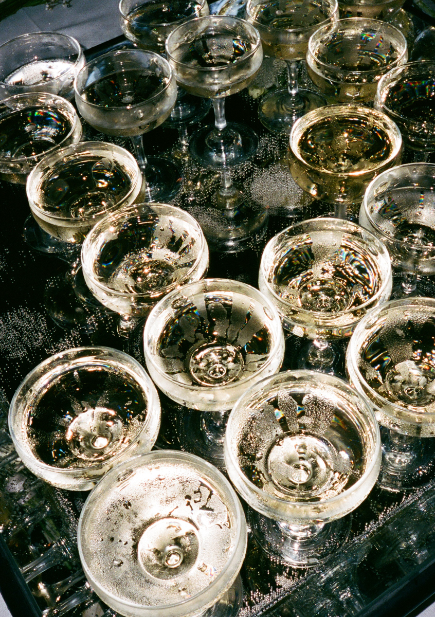 A close-up view of various champagne glasses filled with bubbly liquid, reflecting light and showcasing their unique shapes on a shiny surface.