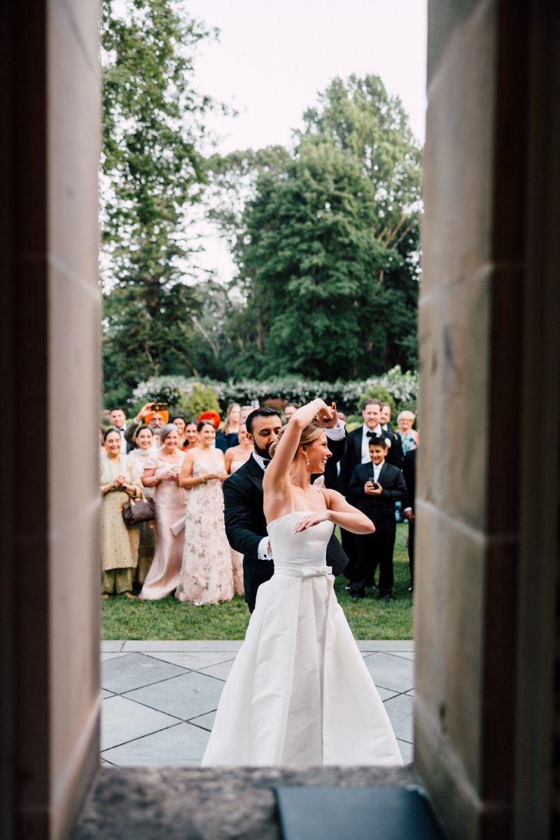 A couple performs a dance amidst an outdoor wedding celebration surrounded by guests.