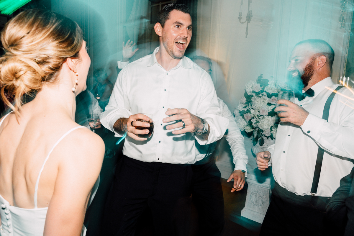 Guests enjoying a lively and energetic dance party with drinks in hand, surrounded by elegant decor.