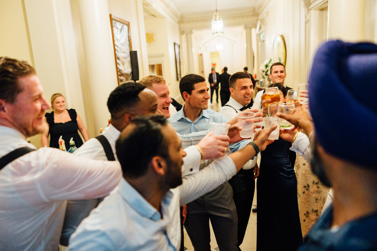 Group of men toasting with drinks in a festive setting, capturing a moment of joy and camaraderie.