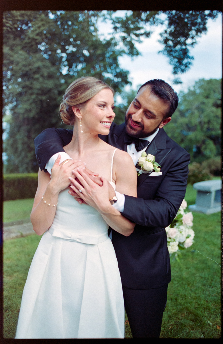 A joyful couple embraces in a lush outdoor setting, showcasing love and happiness on their special day.