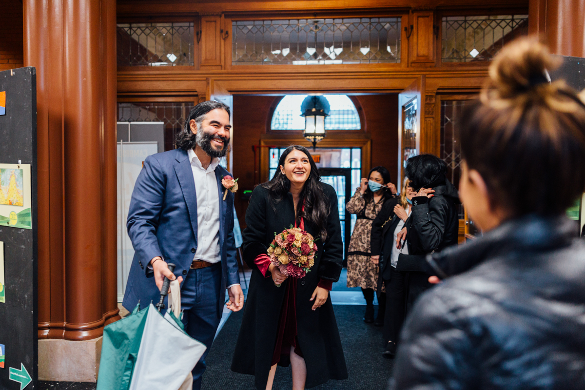 A joyful couple greets guests at an event, surrounded by friends in a beautifully decorated venue.