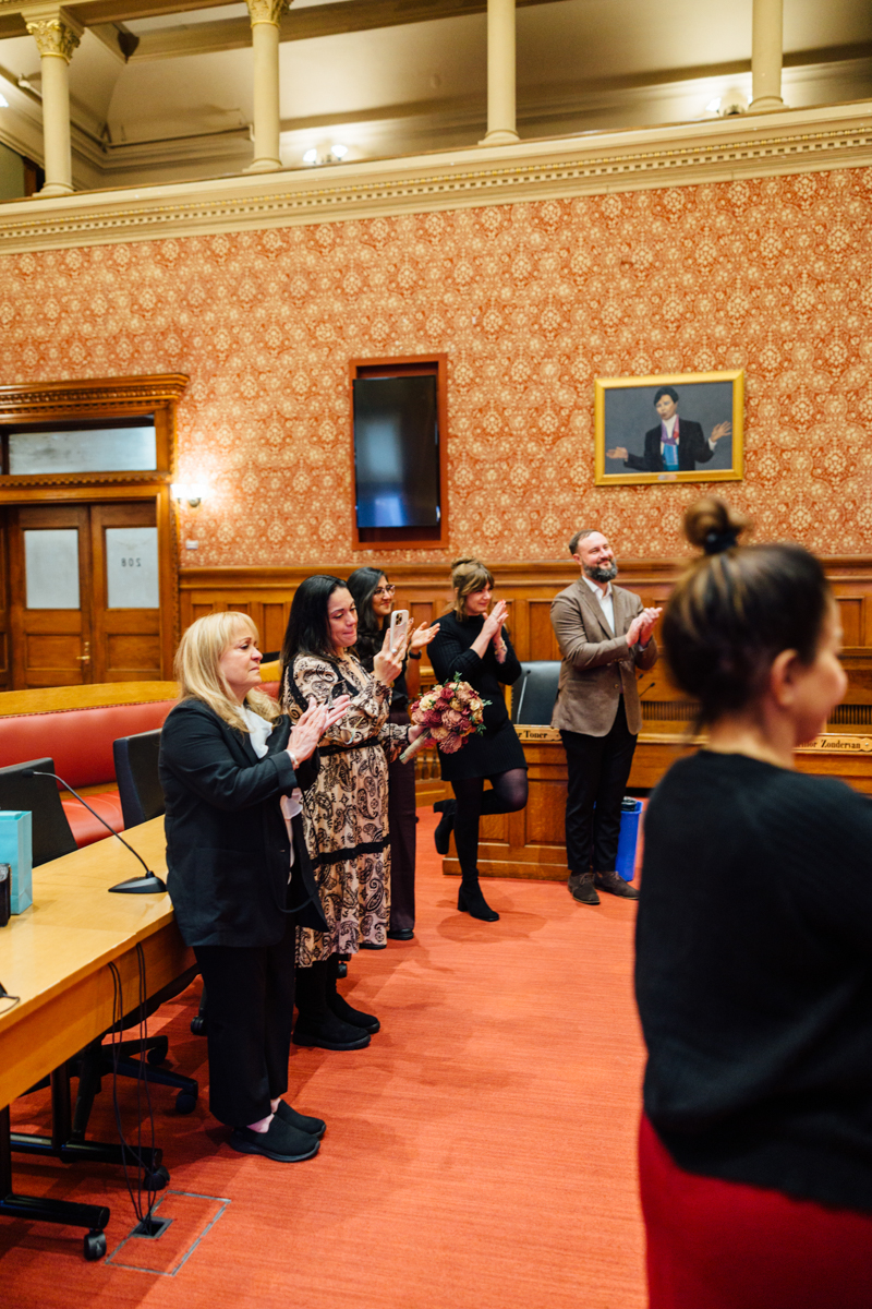 A group of people applauding in a decorative room, showcasing emotional support and celebration.