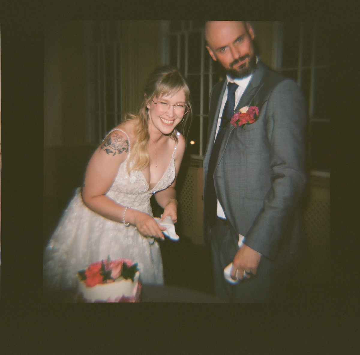 A joyful couple sharing a lighthearted moment at their wedding, with the bride in a sparkling dress and the groom in a gray suit, ready to cut the cake.