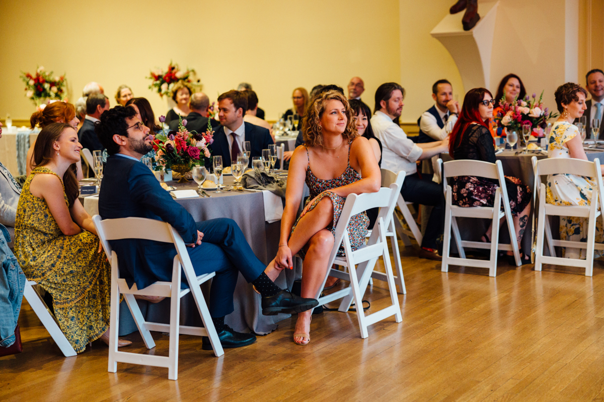 Guests seated at elegantly decorated tables, attentively enjoying a toast during a festive event.