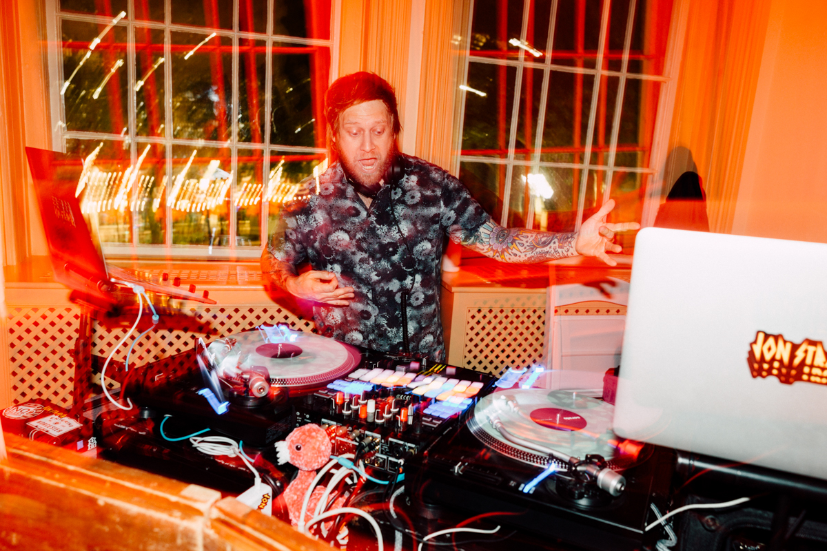 A DJ passionately mixing music behind turntables with colorful lighting and a lively atmosphere.