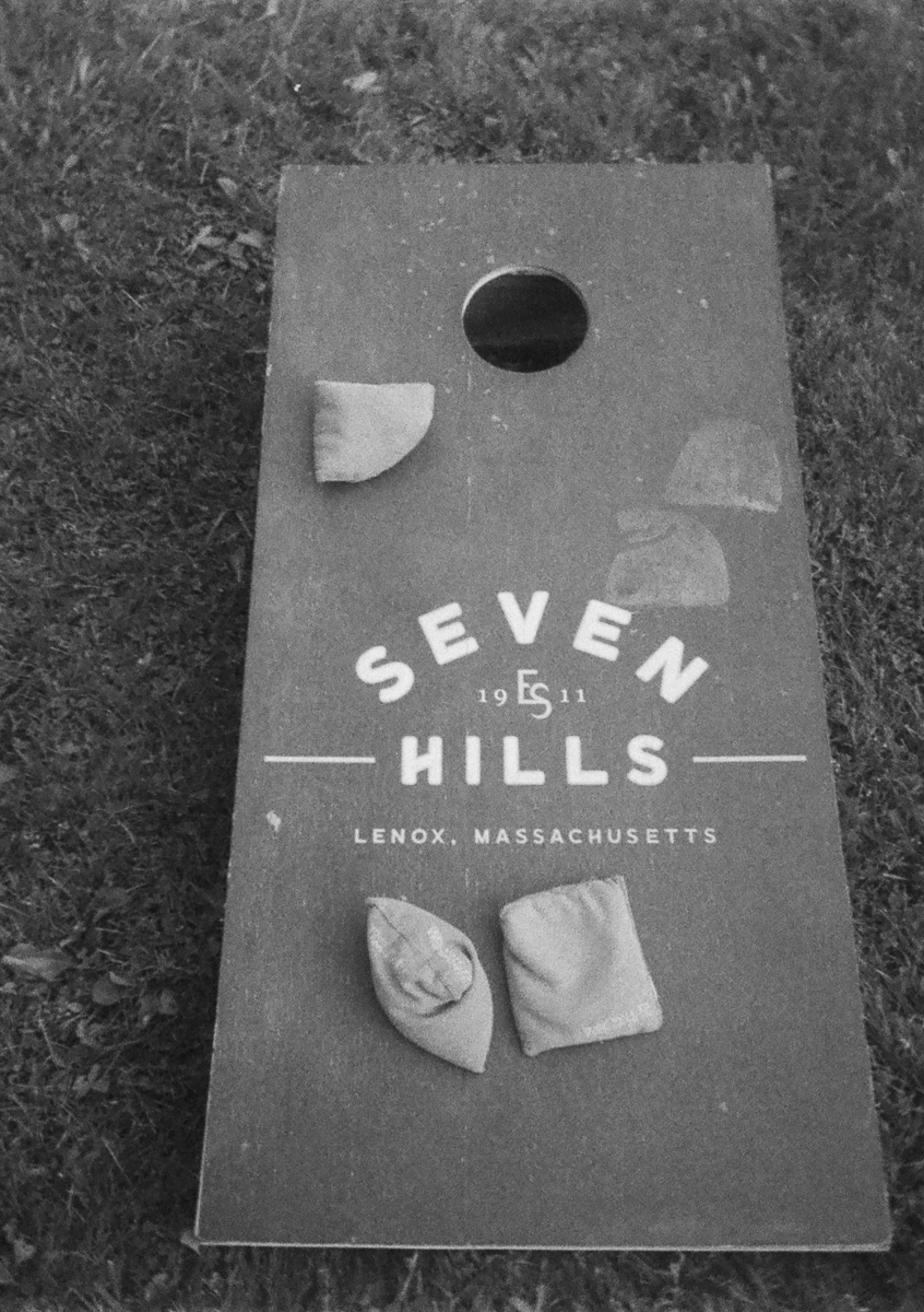A cornhole board on grass with four bean bags and the text Seven Hills 1951 Lenox, MA, perfect for a wedding at the Seven Hills Inn.